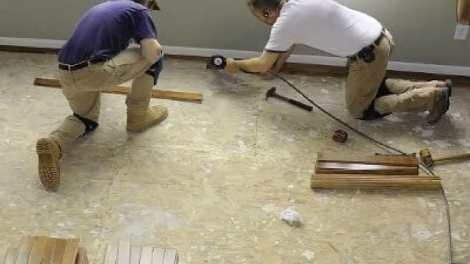 Two contractors on their knees repairing a water-damaged floor